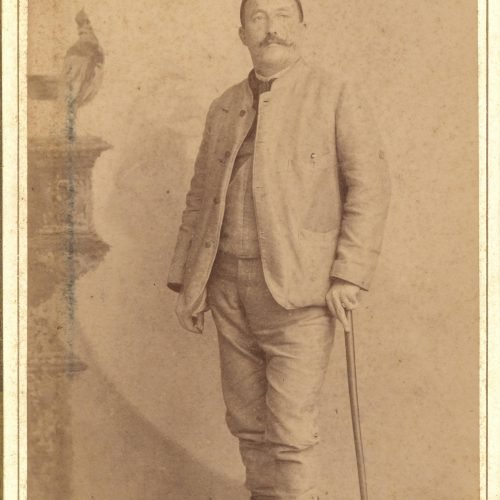 Αχρονολόγητη φωτογραφία άνδρα που φοράει φέσι και κρατά μπαστούνι σ