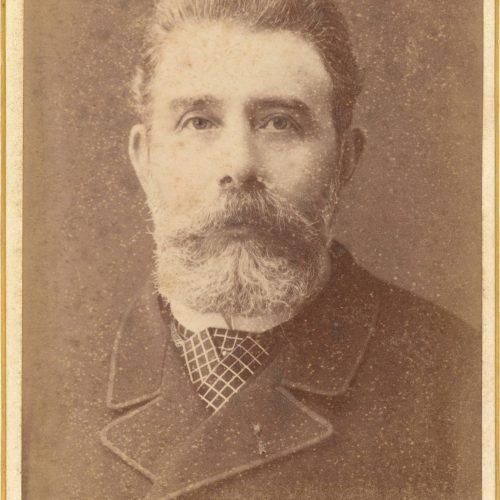 Φωτογραφικό πορτρέτο άνδρα με μουστάκι, γενειάδα και καρό γραβάτα. Ο
