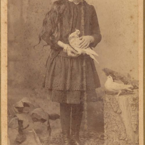 Φωτογραφία κοριτσιού με σκουρόχρωμα ρούχα. Κρατάει πουλί. Ο λογότυπ�