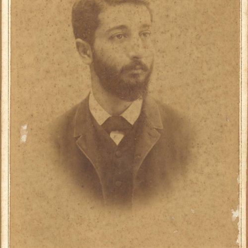 Photographic portrait of a young man with a moustache and a beard. The logo of the photo shop in the lower part of the recto 