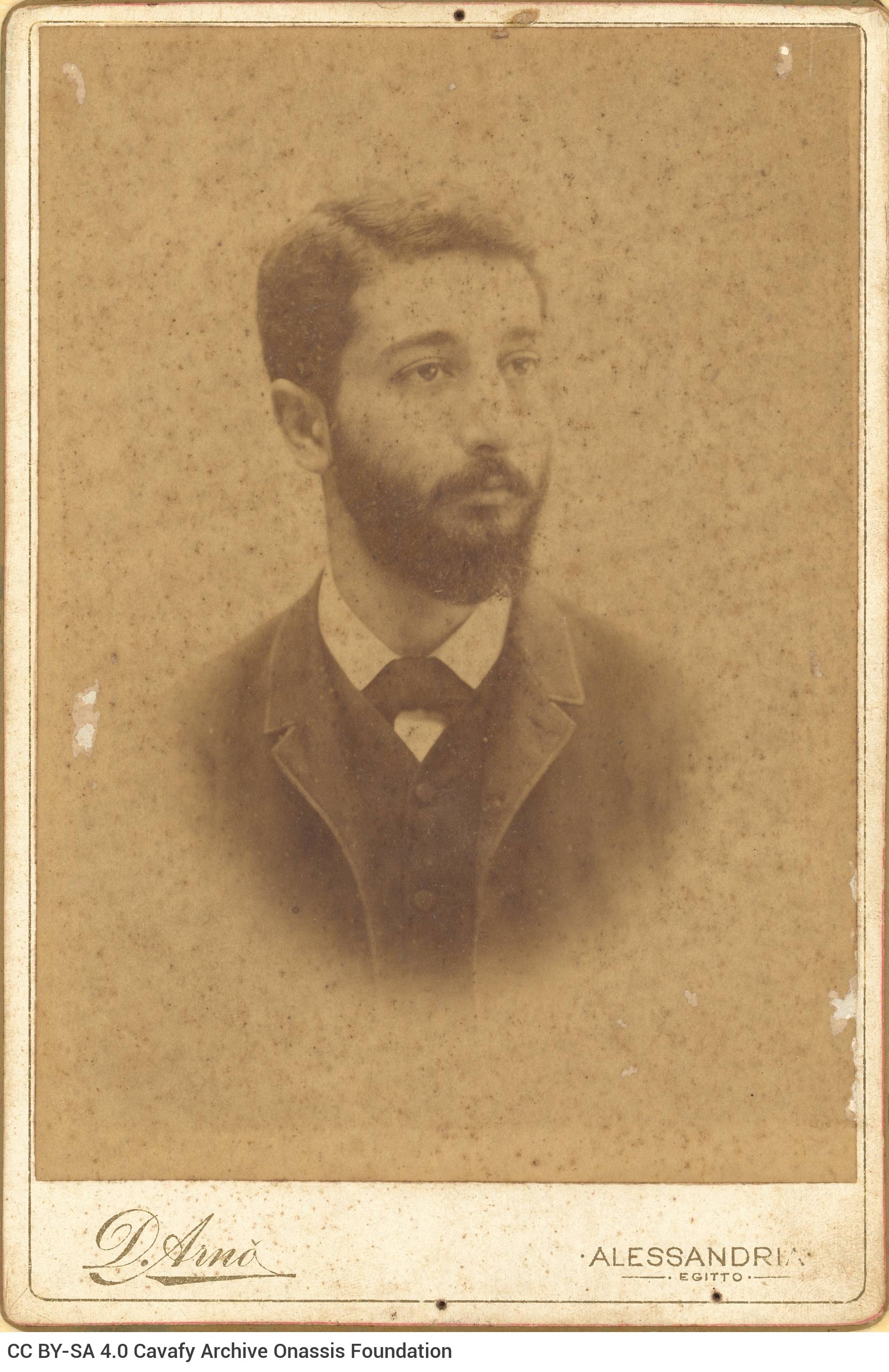 Photographic portrait of a young man with a moustache and a beard. The logo of the photo shop in the lower part of the recto 
