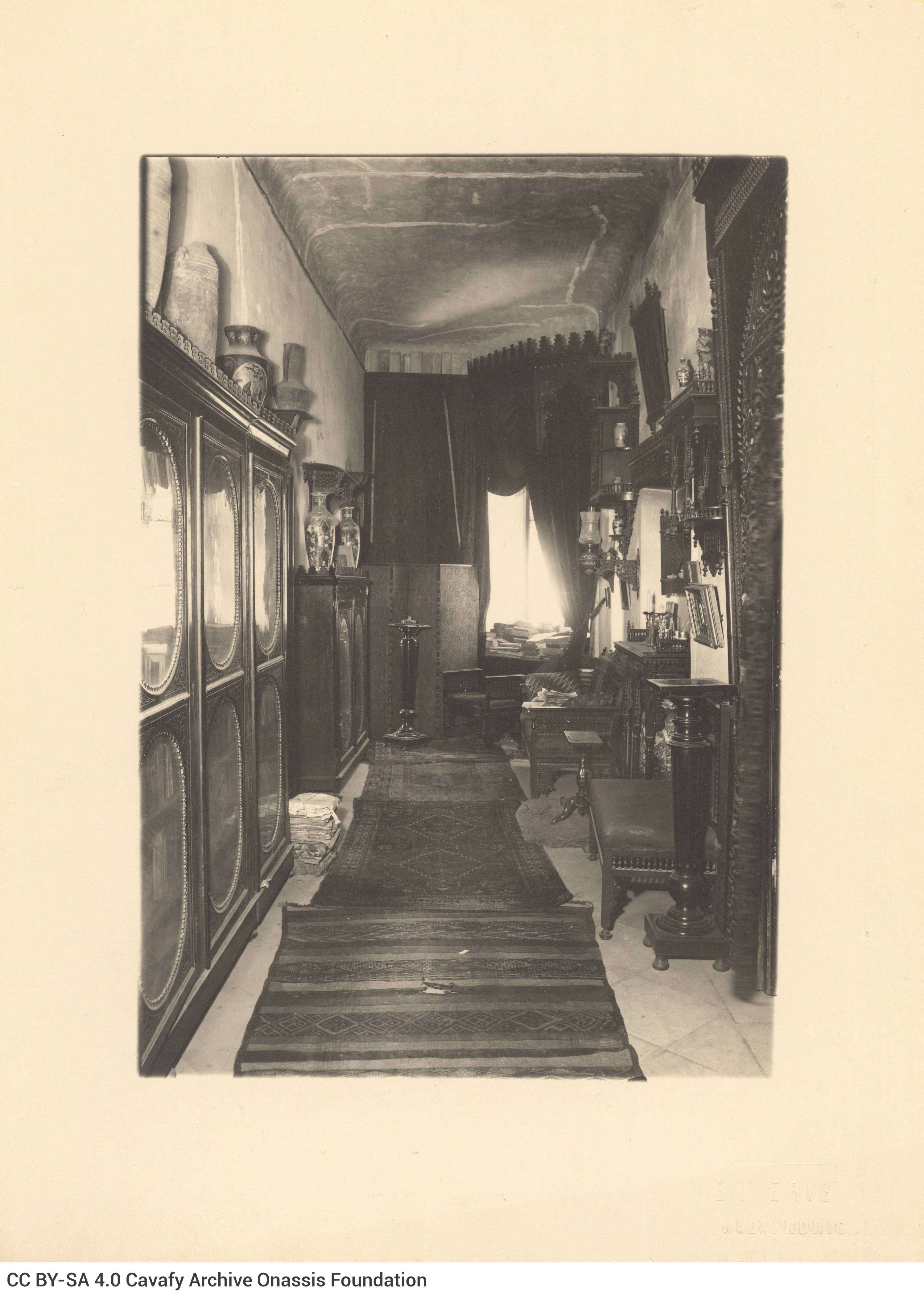 View of the interior of Cavafy's flat on Lepsius street. It depicts a hallway with bookcases and seats, at the end of which i