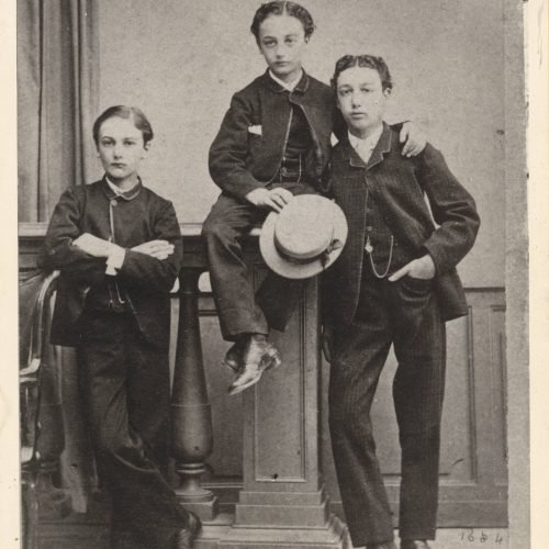 Φωτογραφία τριών αγοριών ντυμένων με κοστούμια. Το αγόρι στο κέντρο 
